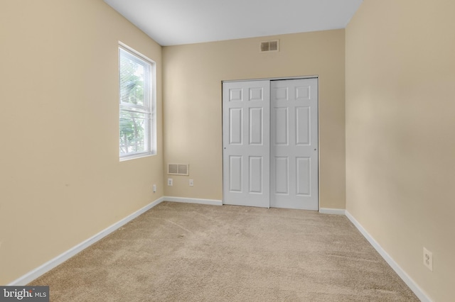 unfurnished bedroom featuring a closet and light carpet