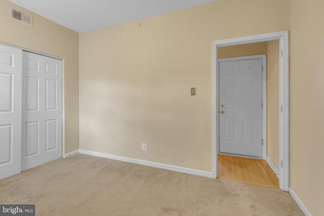 unfurnished bedroom with a closet and light carpet