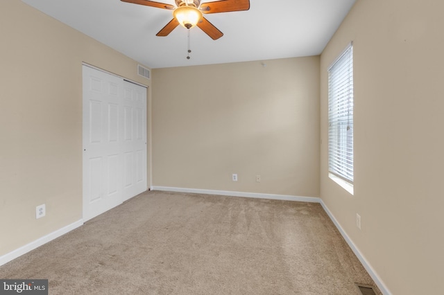 interior space featuring a closet, light colored carpet, and ceiling fan