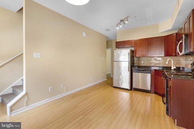 kitchen with appliances with stainless steel finishes, sink, backsplash, and light hardwood / wood-style floors