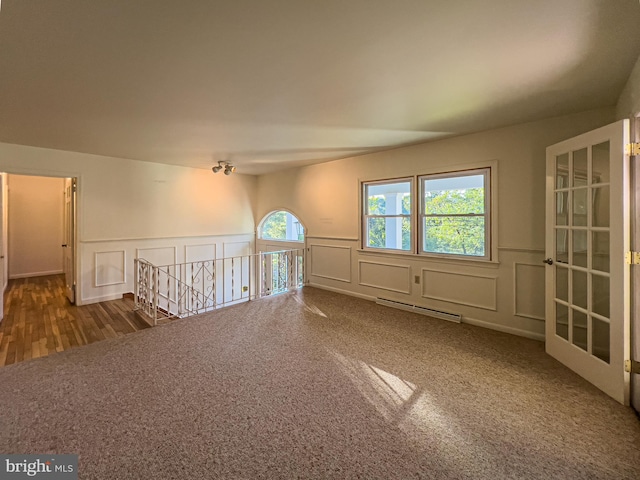 carpeted empty room with a baseboard heating unit