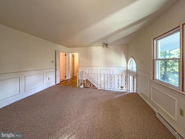 unfurnished room featuring lofted ceiling, carpet, and a baseboard radiator