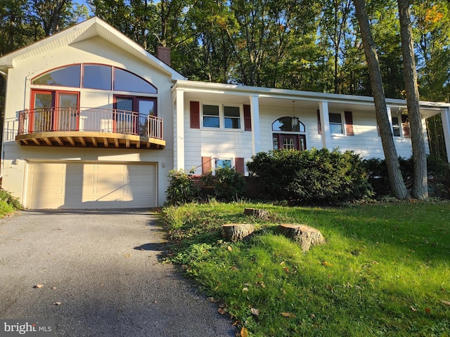 view of front of house featuring a garage, a balcony, and a front lawn