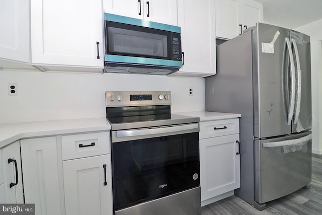 kitchen featuring white cabinets, stainless steel appliances, light countertops, and wood finished floors