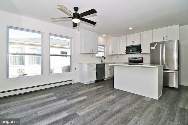 kitchen featuring dark wood-type flooring, stainless steel appliances, light countertops, a baseboard heating unit, and white cabinetry