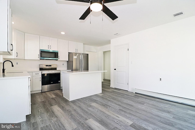 kitchen with dark wood finished floors, stainless steel appliances, visible vents, a sink, and a kitchen island