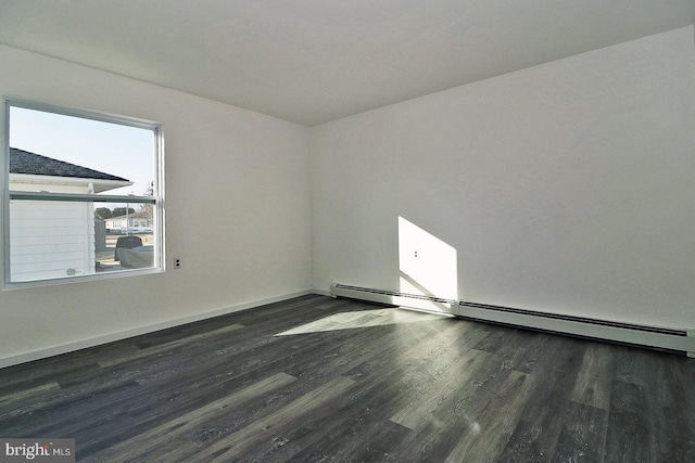 spare room with dark wood-type flooring, baseboard heating, and baseboards