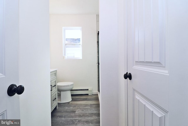 bathroom featuring a baseboard heating unit, toilet, wood finished floors, and vanity