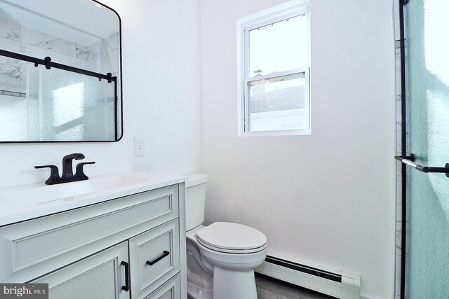 bathroom featuring toilet, a baseboard heating unit, a stall shower, vanity, and wood finished floors