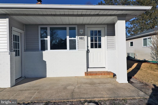 property entrance featuring brick siding and cooling unit