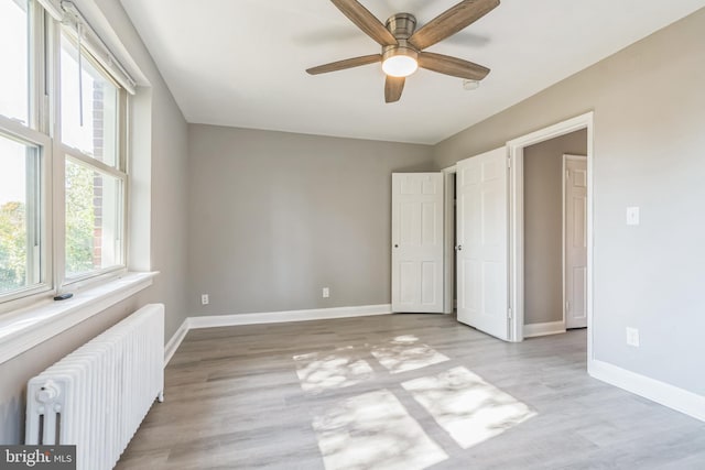 unfurnished bedroom with light hardwood / wood-style flooring, radiator heating unit, and ceiling fan