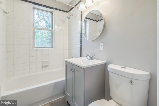 full bathroom featuring vanity, tiled shower / bath combo, and toilet