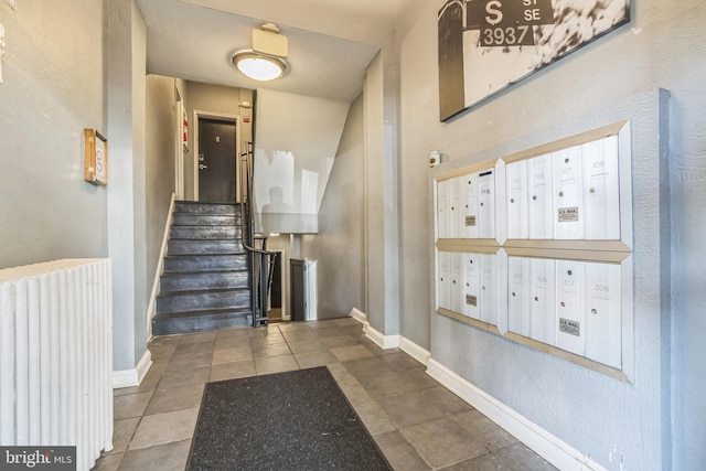 staircase with mail boxes, radiator, and tile patterned floors