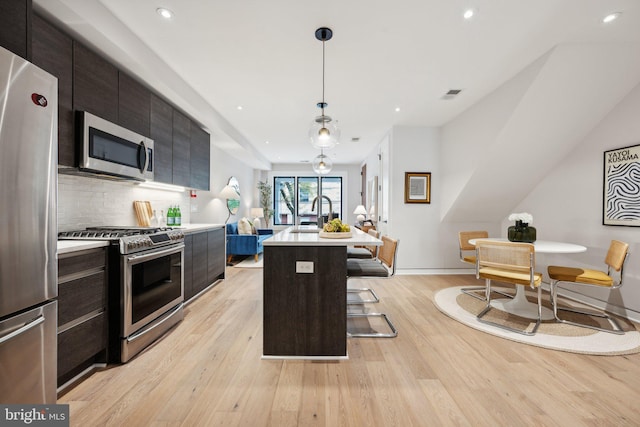 kitchen with pendant lighting, a center island, light hardwood / wood-style flooring, and stainless steel appliances