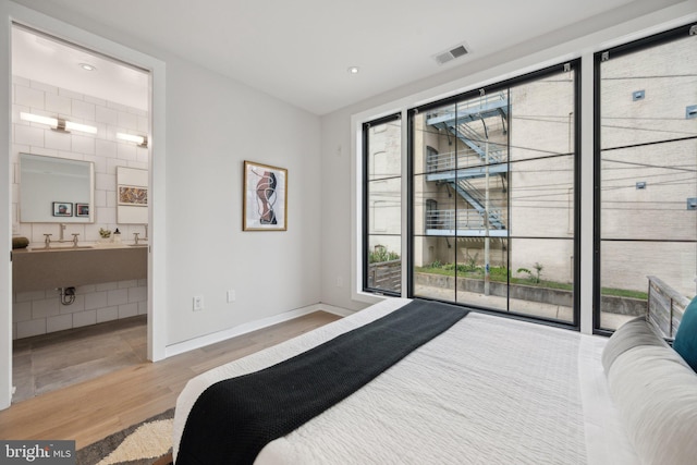 bedroom with light hardwood / wood-style flooring, access to exterior, and connected bathroom