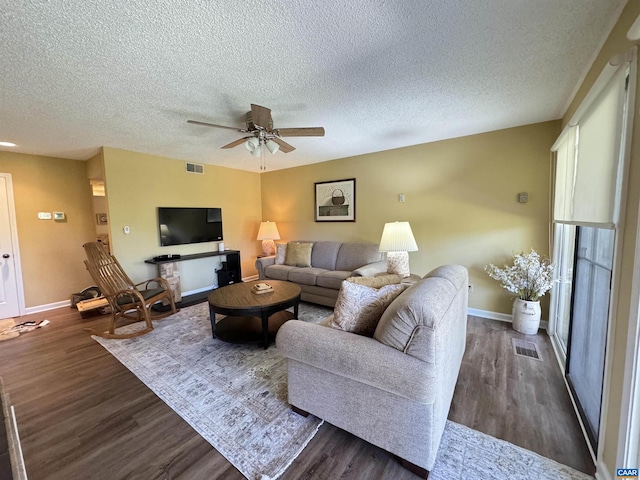 living room featuring dark wood-type flooring, a textured ceiling, and ceiling fan