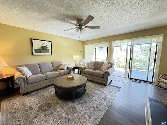 living room with ceiling fan, dark hardwood / wood-style floors, and a textured ceiling