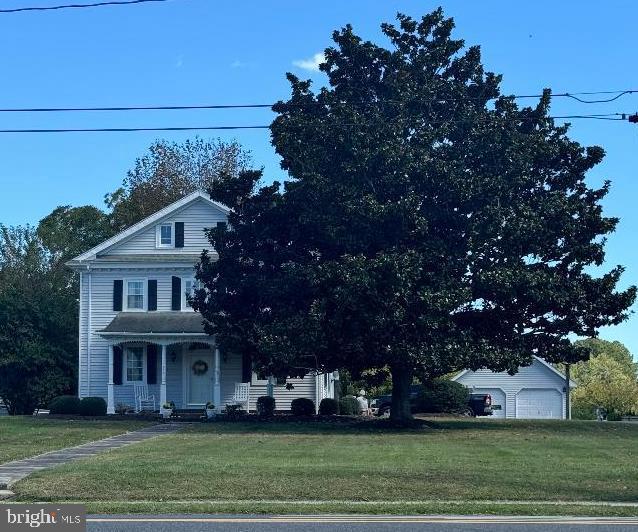 view of front of property featuring a porch, a front lawn, and a garage