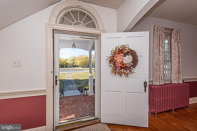 foyer featuring radiator heating unit, hardwood / wood-style flooring, and vaulted ceiling