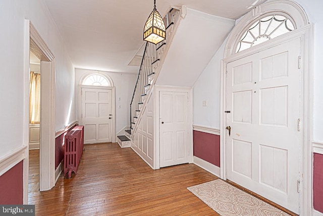 foyer with wood-type flooring and vaulted ceiling