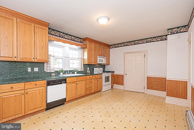 kitchen featuring tasteful backsplash, sink, baseboard heating, wooden walls, and white appliances