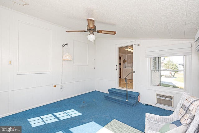 unfurnished room featuring an AC wall unit, a textured ceiling, carpet, and vaulted ceiling