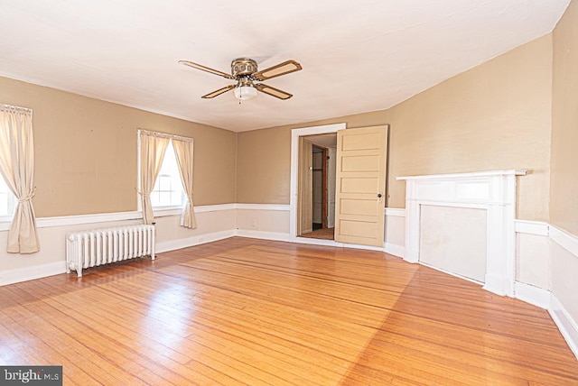 empty room with ceiling fan, light hardwood / wood-style floors, and radiator