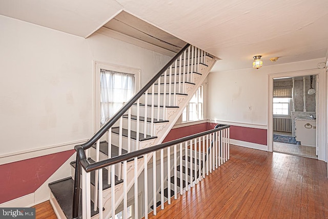 stairway with hardwood / wood-style flooring and radiator heating unit