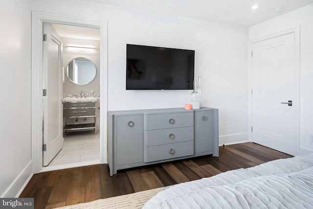 bedroom with dark hardwood / wood-style floors, sink, and connected bathroom