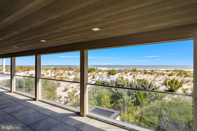 unfurnished sunroom with a water view and wooden ceiling