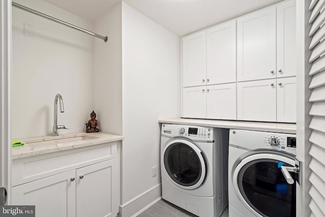 laundry room with cabinets, washing machine and dryer, and sink