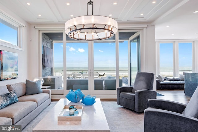 living room with a chandelier, light wood-type flooring, and a water view