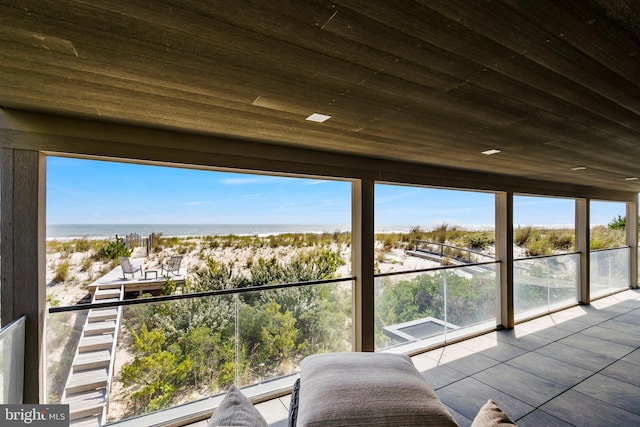 unfurnished sunroom with a healthy amount of sunlight, a water view, and wooden ceiling