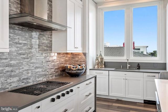 kitchen with white cabinetry, sink, dark wood-type flooring, wall chimney range hood, and decorative backsplash