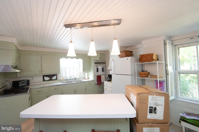 kitchen with hanging light fixtures, sink, white fridge, a center island, and green cabinetry