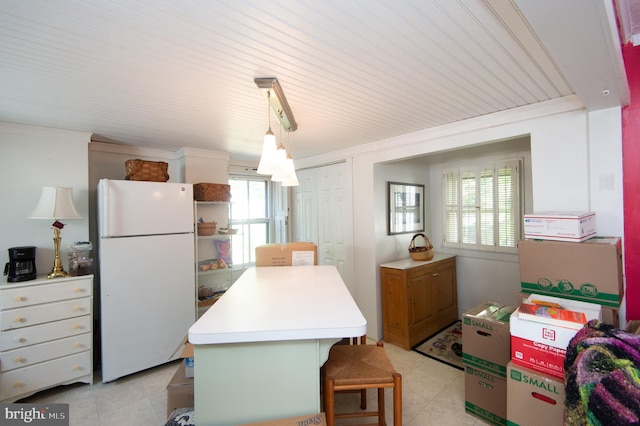 kitchen featuring plenty of natural light, a kitchen bar, pendant lighting, and white refrigerator