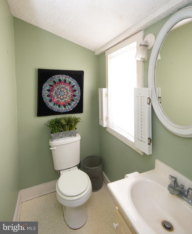 bathroom featuring toilet, a textured ceiling, and sink