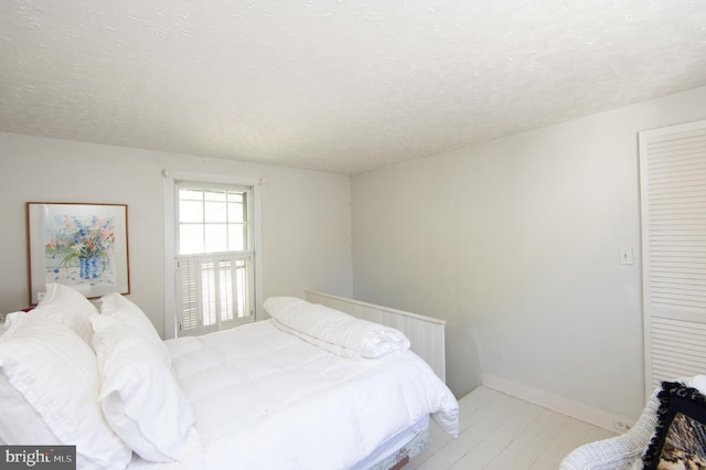 bedroom featuring light hardwood / wood-style floors and a textured ceiling