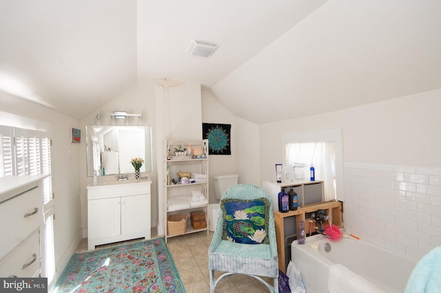 bathroom featuring vanity, vaulted ceiling, tile patterned flooring, and a bathing tub