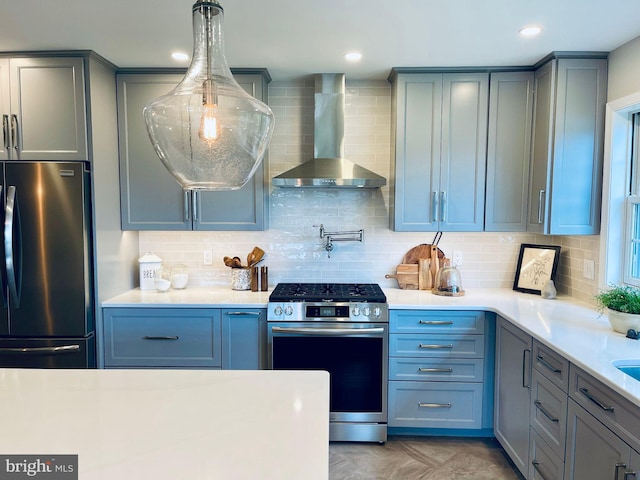 kitchen featuring pendant lighting, stainless steel appliances, tasteful backsplash, and wall chimney range hood