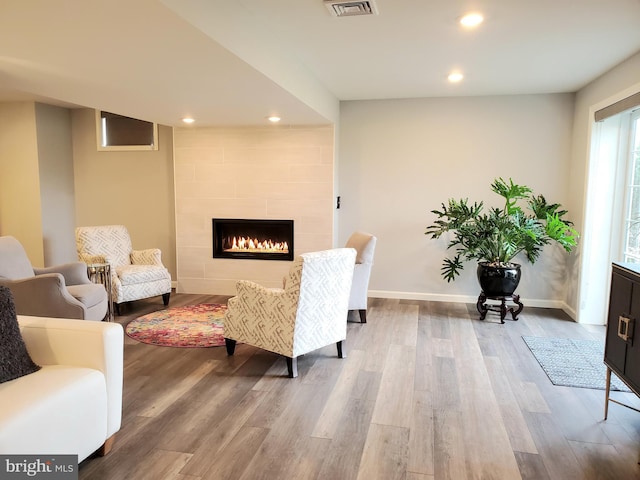 living area featuring hardwood / wood-style flooring and a tiled fireplace