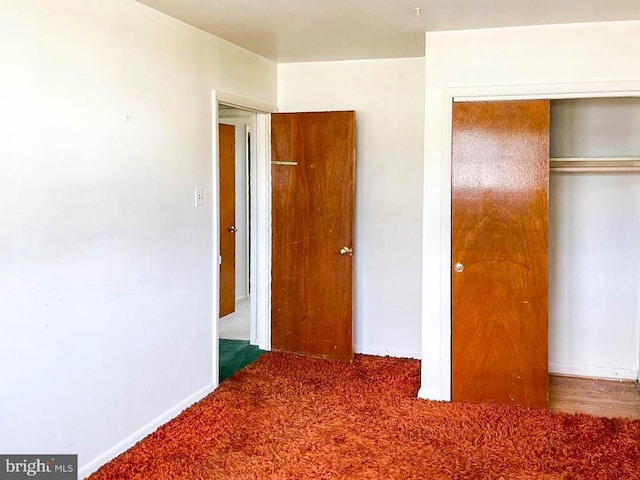 unfurnished bedroom featuring dark colored carpet and a closet