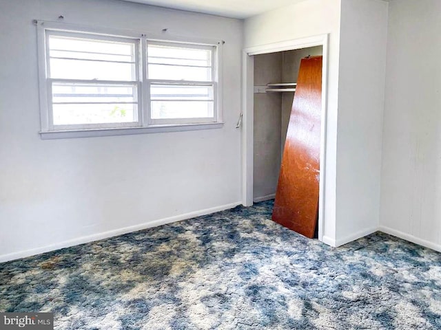 unfurnished bedroom with a closet and dark carpet