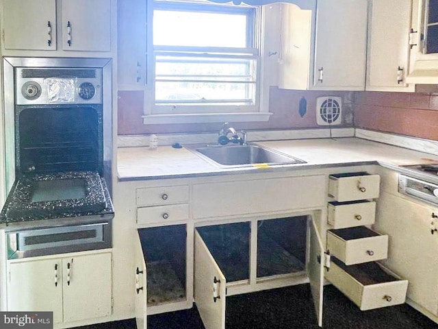 kitchen featuring stainless steel gas cooktop, sink, decorative backsplash, and white cabinetry