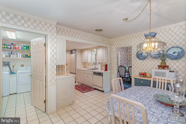 kitchen featuring washing machine and clothes dryer, sink, crown molding, decorative light fixtures, and white appliances