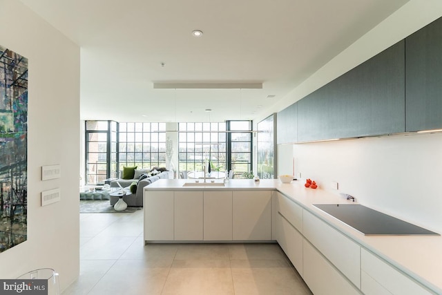 kitchen with expansive windows, sink, kitchen peninsula, light tile patterned floors, and black electric stovetop