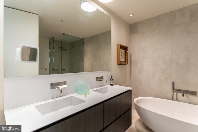 bathroom featuring tile patterned flooring, tile walls, vanity, and independent shower and bath