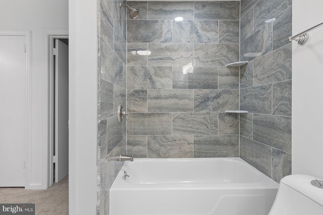 bathroom featuring tiled shower / bath combo and toilet