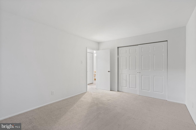 unfurnished bedroom featuring a closet and light colored carpet