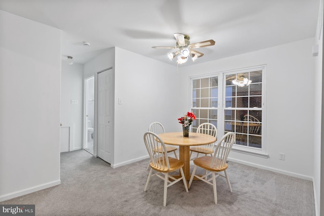 dining area with ceiling fan and light colored carpet